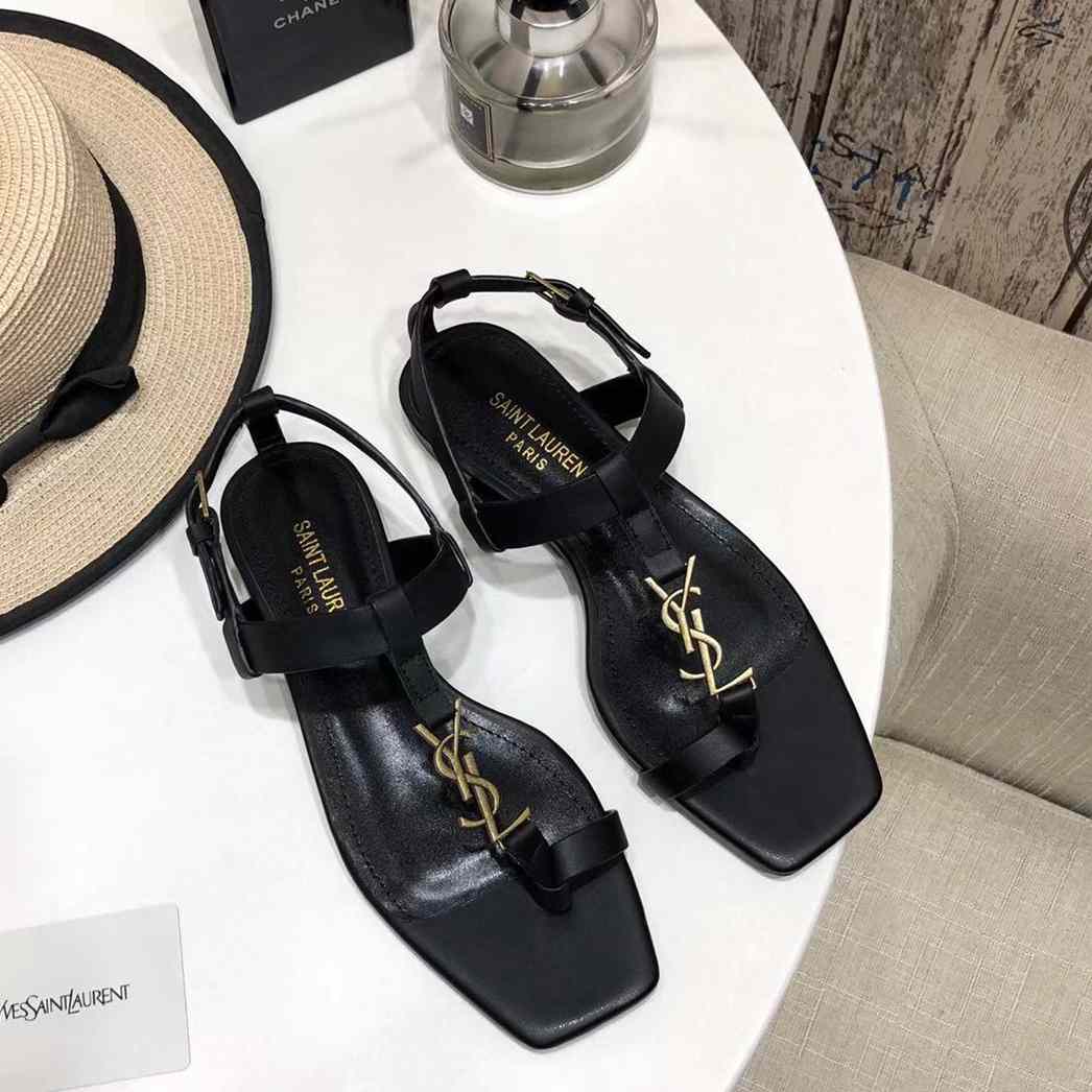 Saint Laurent – ​​Flache Cassandra-Sandalen aus Glattleder mit goldfarbenem Monogramm - EUR FASHION