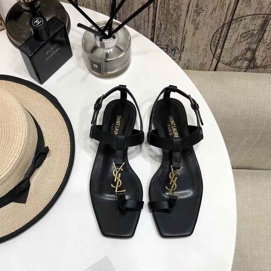 Saint Laurent – ​​Flache Cassandra-Sandalen aus Glattleder mit goldfarbenem Monogramm - EUR FASHION