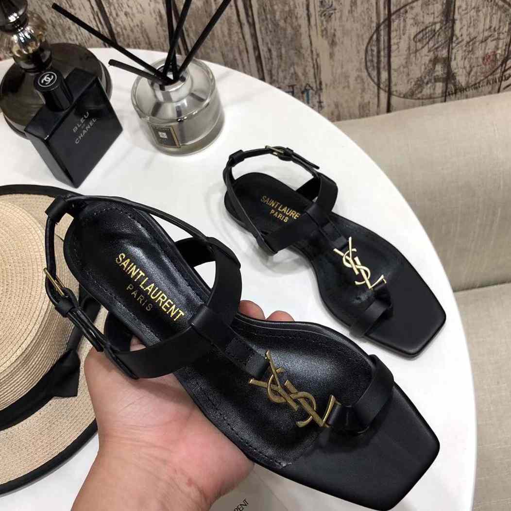 Saint Laurent – ​​Flache Cassandra-Sandalen aus Glattleder mit goldfarbenem Monogramm - EUR FASHION